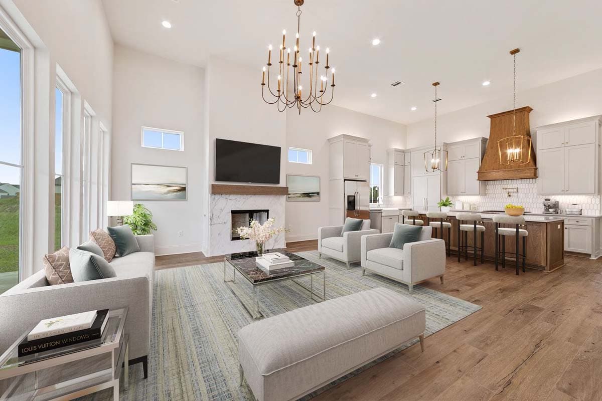 Open-concept living and kitchen area featuring a marble fireplace, large windows, island seating, and a wooden range hood.
