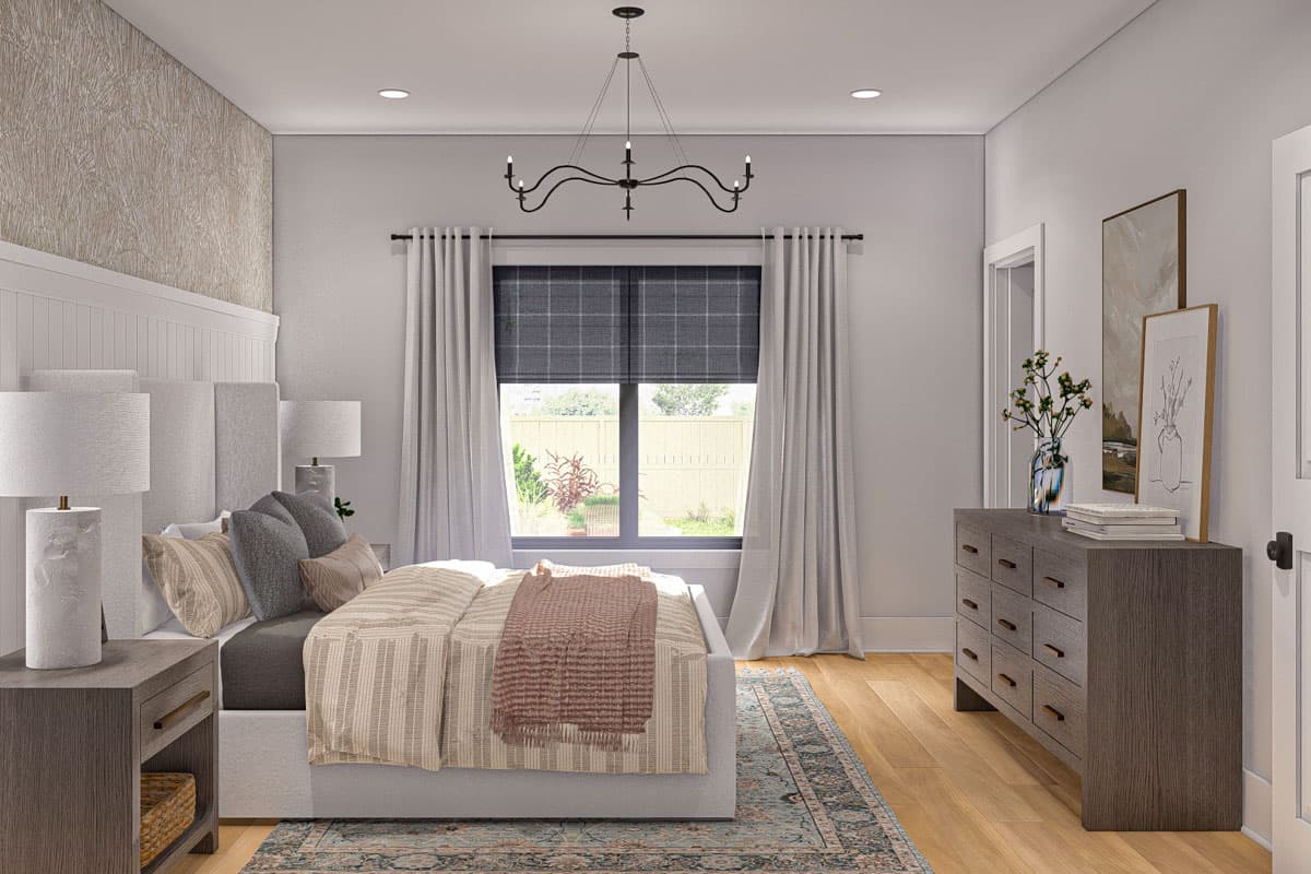 Bedroom with large window, decorative headboard, bedside tables with lamps, and dresser with art.