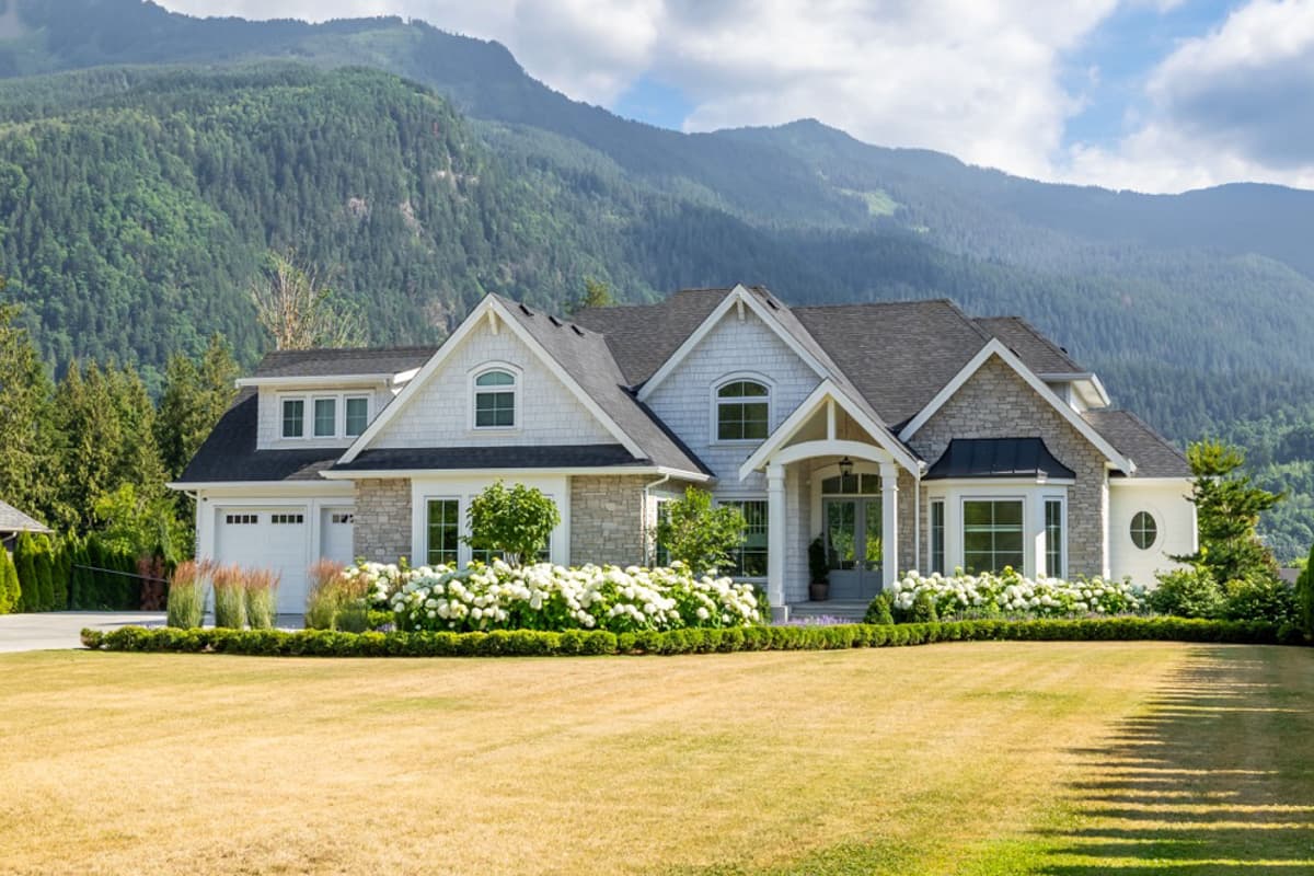 House plan exterior: Two-story Modern Farmhouse with stone accents, covered entry, dormers, and a three-car garage.