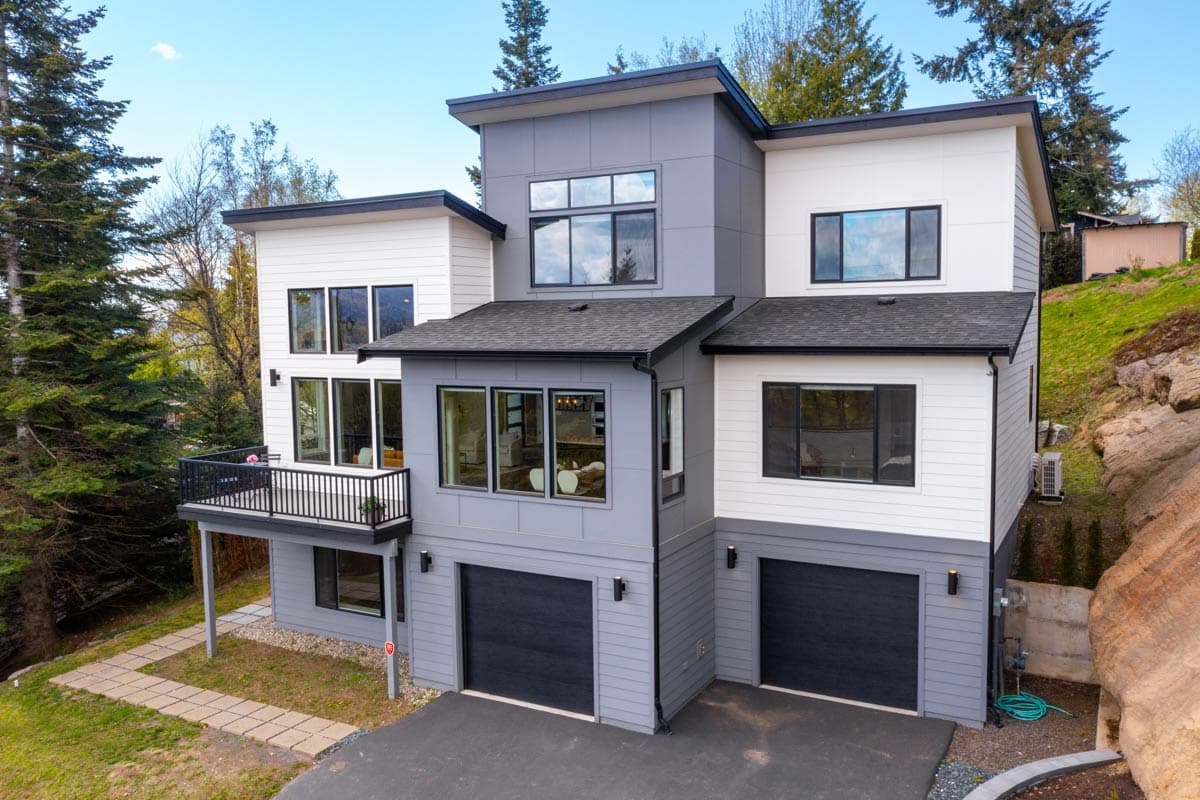 Modern house plan exterior with multiple stories, flat rooflines, large windows, a balcony, and a two-car garage.