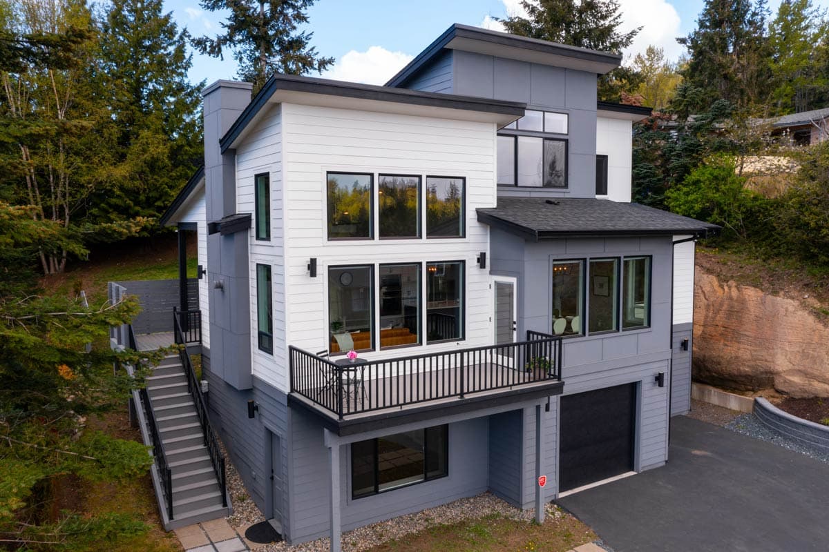 Modern house plan exterior with multiple stories, balcony, large windows, and integrated garage.