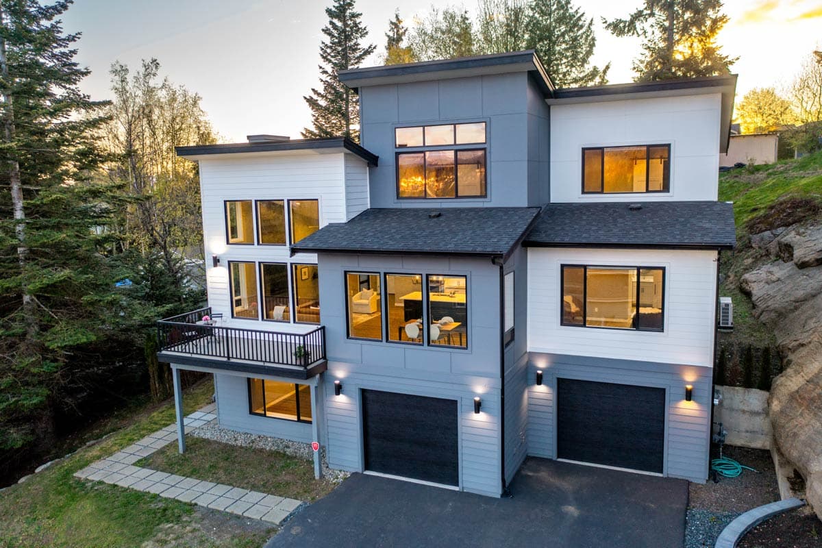 Modern house plan exterior, 3 stories, with a balcony, multiple gables, and a two-car garage.