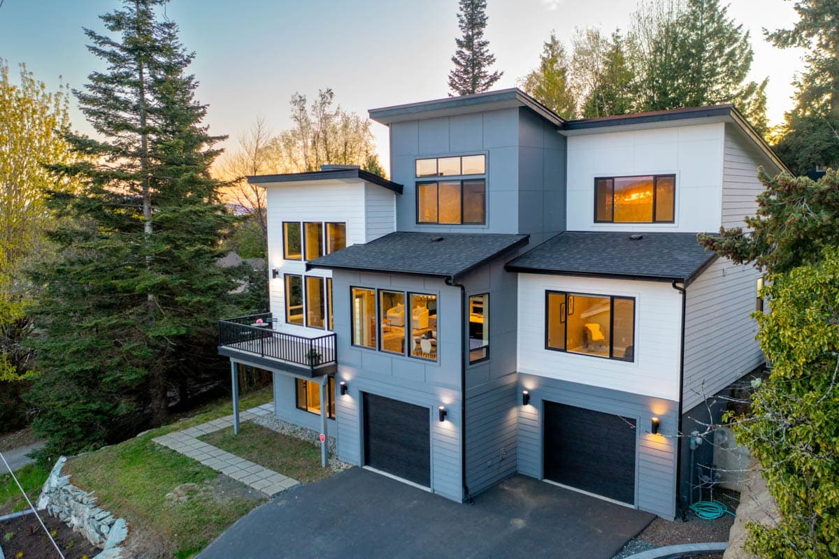 Modern house plan exterior with multiple gables, a cantilevered balcony, and a three-car garage.