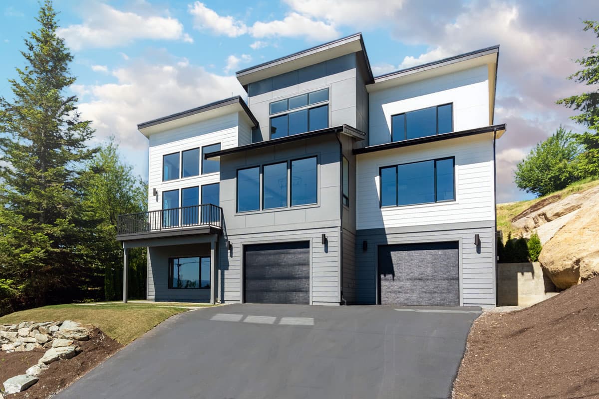 House plan exterior. Modern style, two-story home with flat and angled rooflines. Features include a balcony, multi-pane windows, and two-car garage.