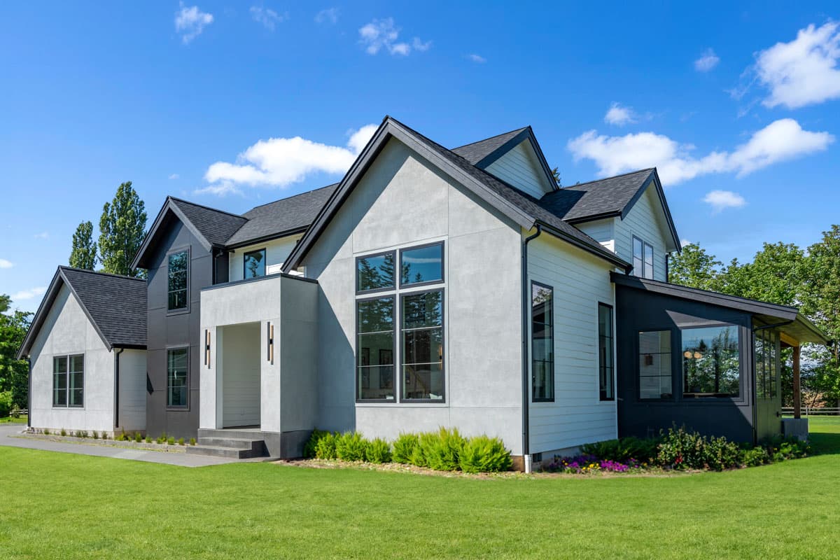 Modern house plan exterior with multiple gables, contrasting stucco and siding, and large black-framed windows.