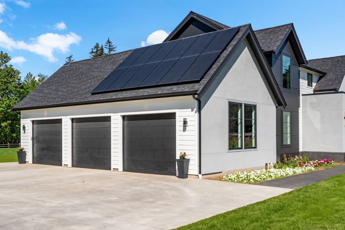 Modern house plan exterior with three-car garage, stucco siding, and solar panels on roof.