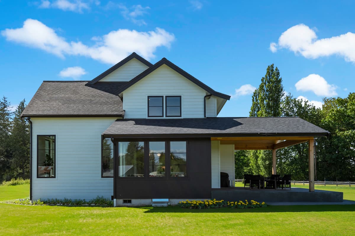 Modern Farmhouse house plan exterior with white siding, gables, dark trim windows, and covered patio.
