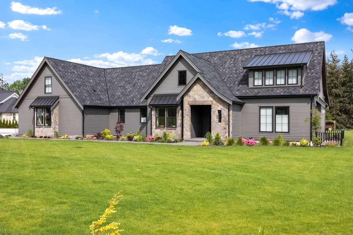 House plan exterior with stone accents, multiple gables, and a mix of horizontal and vertical siding. Features a covered entry and dormer.