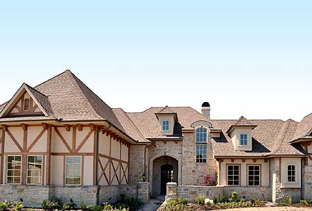 House plan exterior with stone facade, arched entryway, dormers, and half-timbered gable.