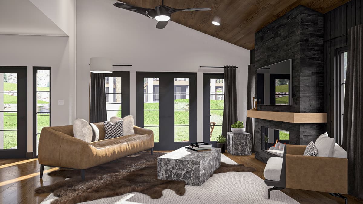 Living room interior with vaulted wood ceiling, stone fireplace, leather sofa, and large windows.
