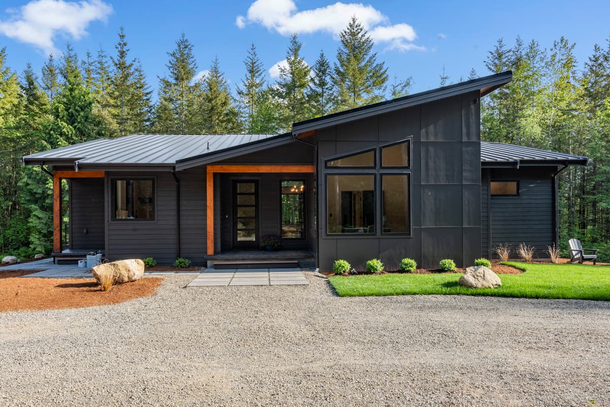 House plan exterior. Modern style, single story. Features include an asymmetrical roofline, large picture windows, and wood-wrapped entry posts.