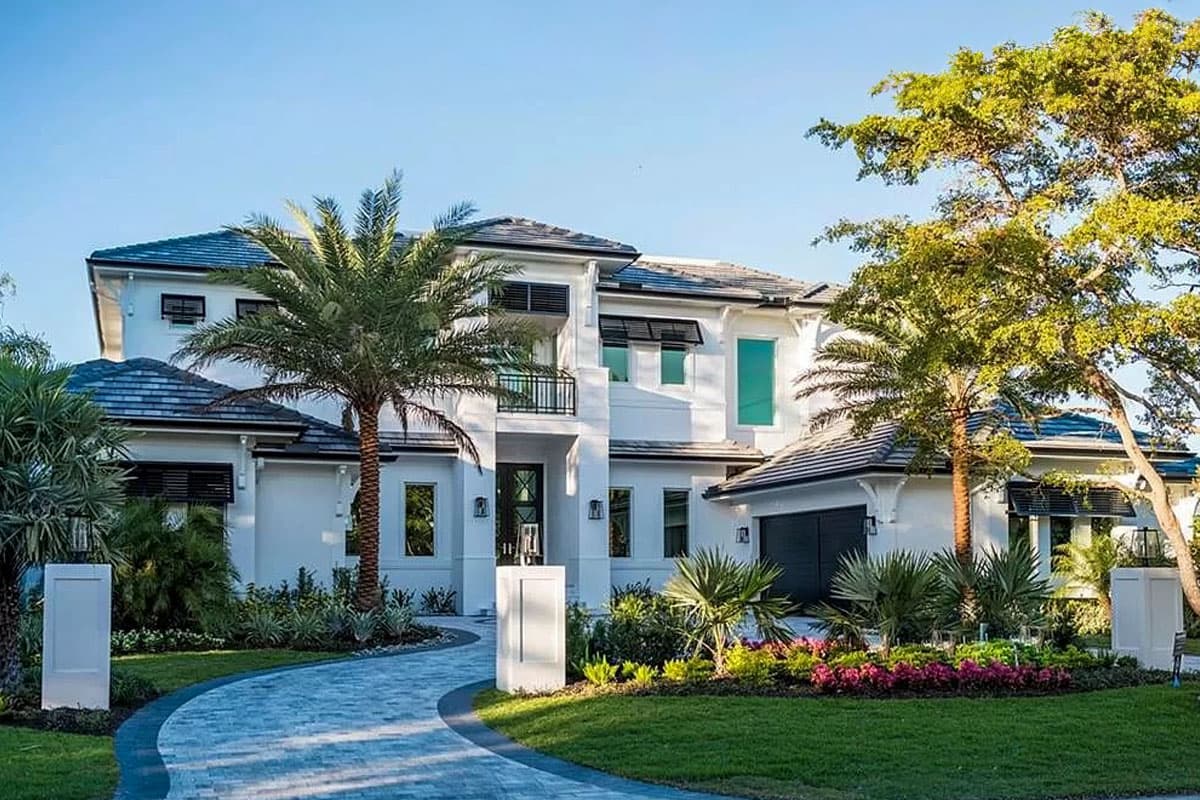 House plan exterior. Two-story Modern house with a hipped roof, balconies, and a two-car garage. Driveway leads to front entrance.