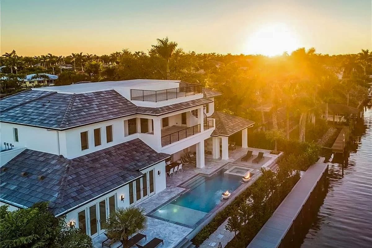 Modern three-story house plan exterior with flat roof, balconies, large windows, and waterfront dock.