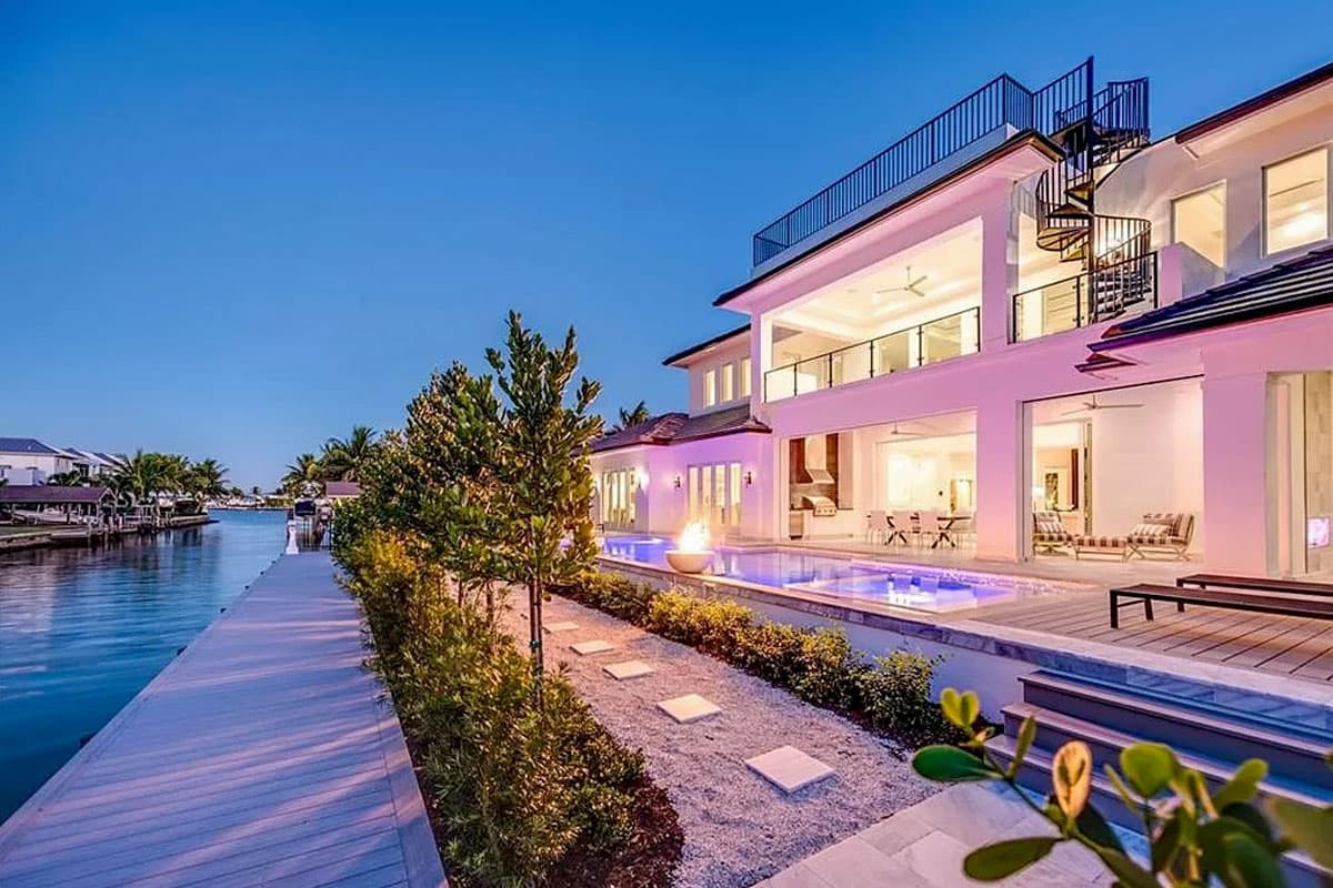 Modern multi-story house plan with a rooftop deck, exterior spiral staircase, and rear-facing infinity pool.