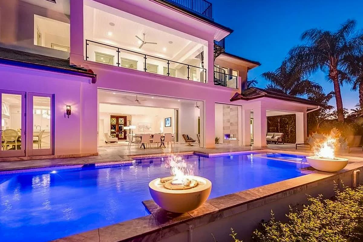 Modern house plan exterior with swimming pool, retractable glass walls, second-story balcony, and outdoor fireplace.