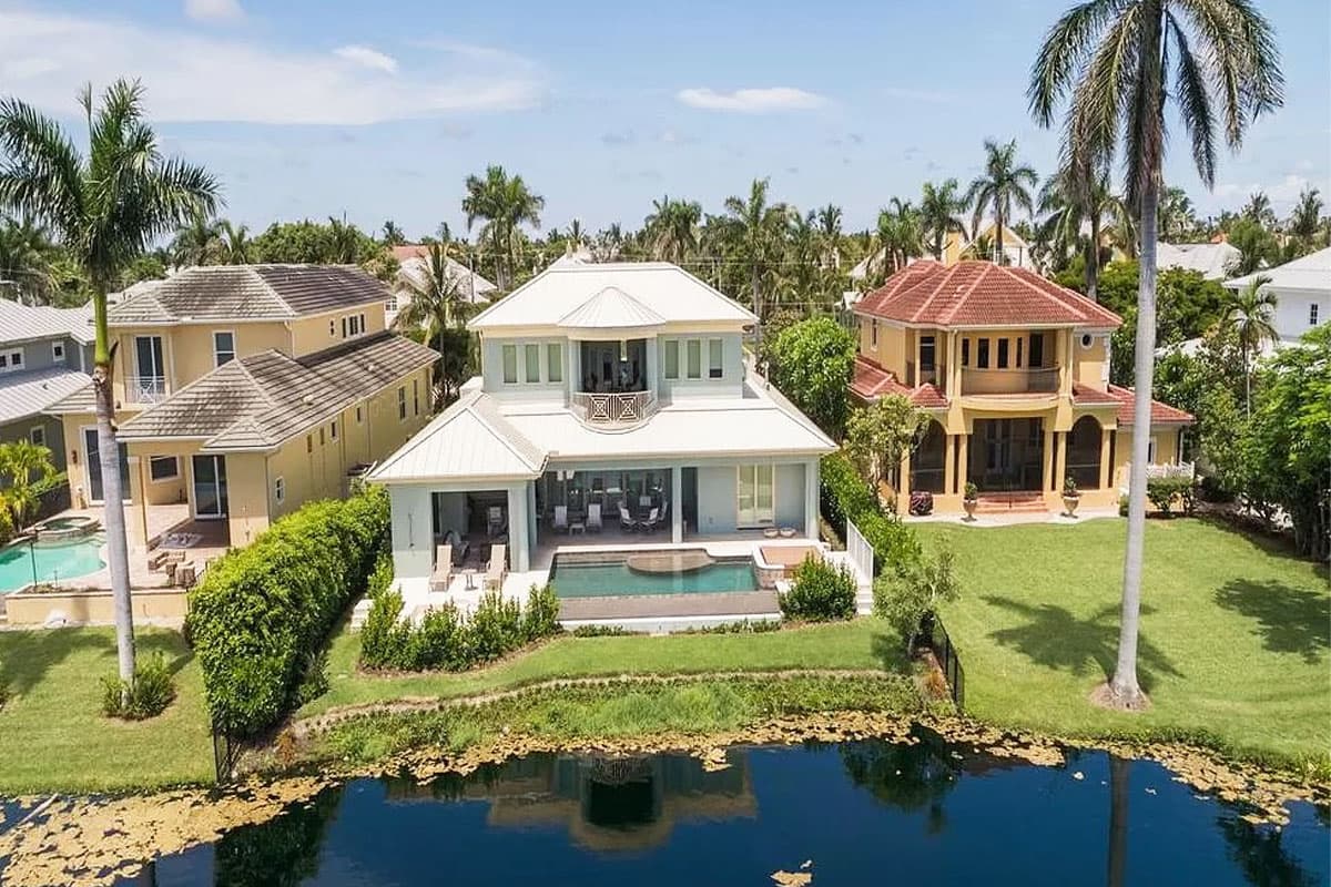 Modern house plan exterior with a metal hip roof, a covered lanai with pool, and a second-story balcony.