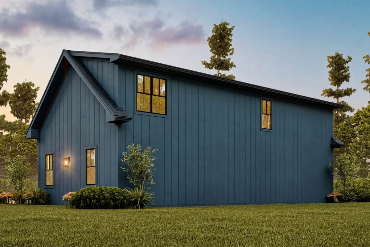 A modern house with blue siding, black trim, and large windows. It is set in a grassy yard, surrounded by trees.