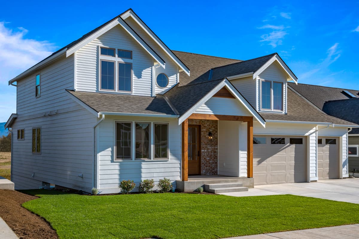 House plan exterior: Two-story Modern Farmhouse with gabled dormers, a covered entry porch with brick accents, and a three-car garage.