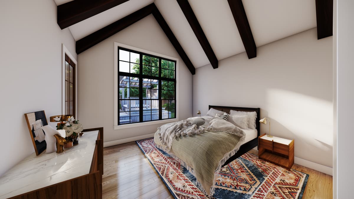 Bedroom interior with vaulted ceiling, exposed beams, large grid window, and bed with patterned rug.