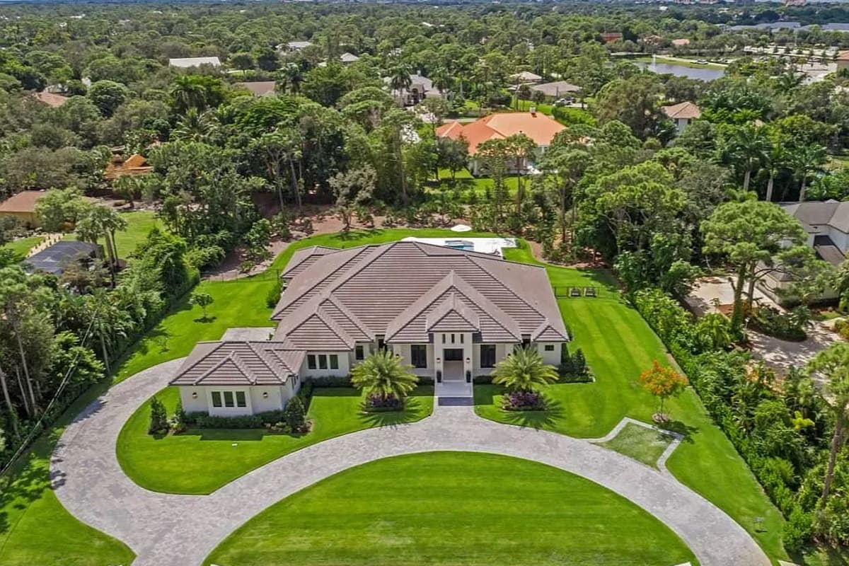 House plan exterior: Contemporary style, one-story residence with a prominent entryway, hip rooflines, and a curved driveway.