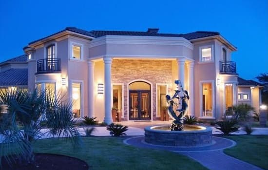 Two-story house plan exterior with arched entry, stone accents, columns, multiple balconies, and a fountain.