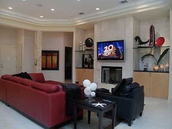 Interior view of a living room with a fireplace, mounted TV, and red sectional sofa.