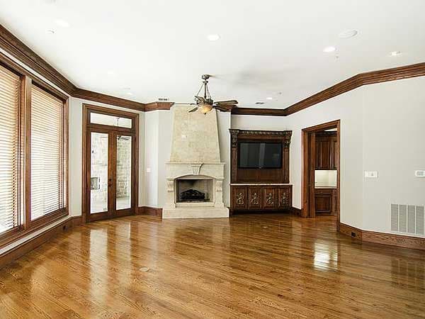 Living room with stone fireplace, built-in entertainment center, large windows, and French doors to exterior.