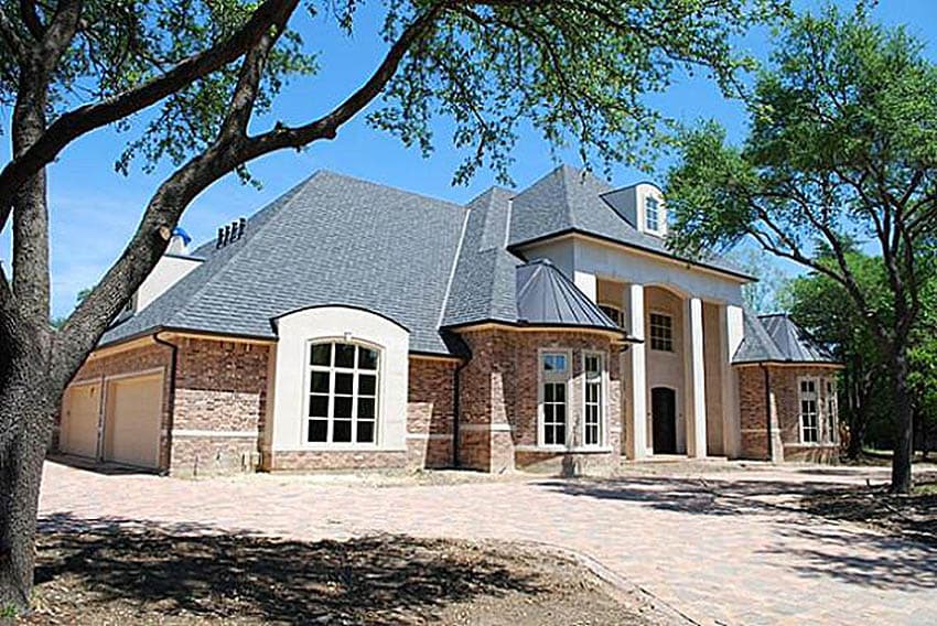 House plan exterior: Two-story home with arched windows, a porte-cochère, multi-level rooflines, and a three-car garage.