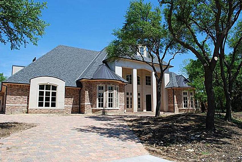 House plan exterior: Large two-story residence with brick accents, prominent portico, and bay windows.