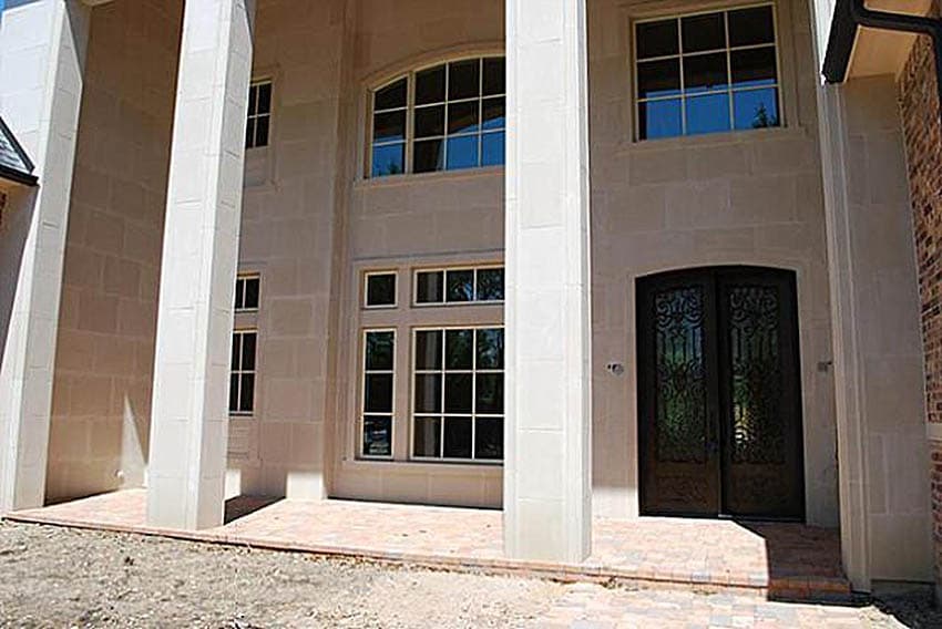 House plan exterior with stone facade, large arched window, and double wrought iron doors.