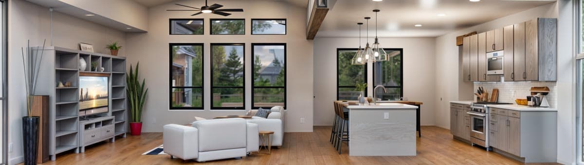 Open-concept living area with vaulted ceiling, large windows, and modern kitchen with island.