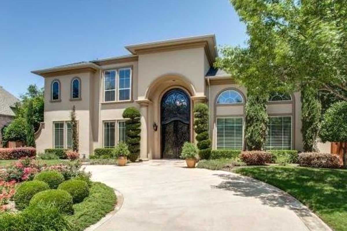 Two-story house plan exterior with arched entryway, arched windows on second floor, and symmetrical landscaping.
