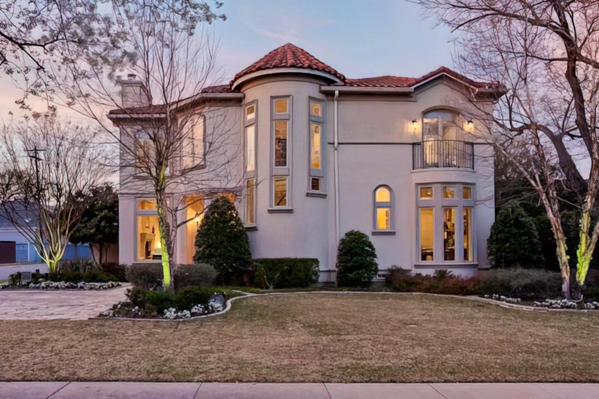 House plan exterior of a two-story home with a turret, arched windows, and a balcony.