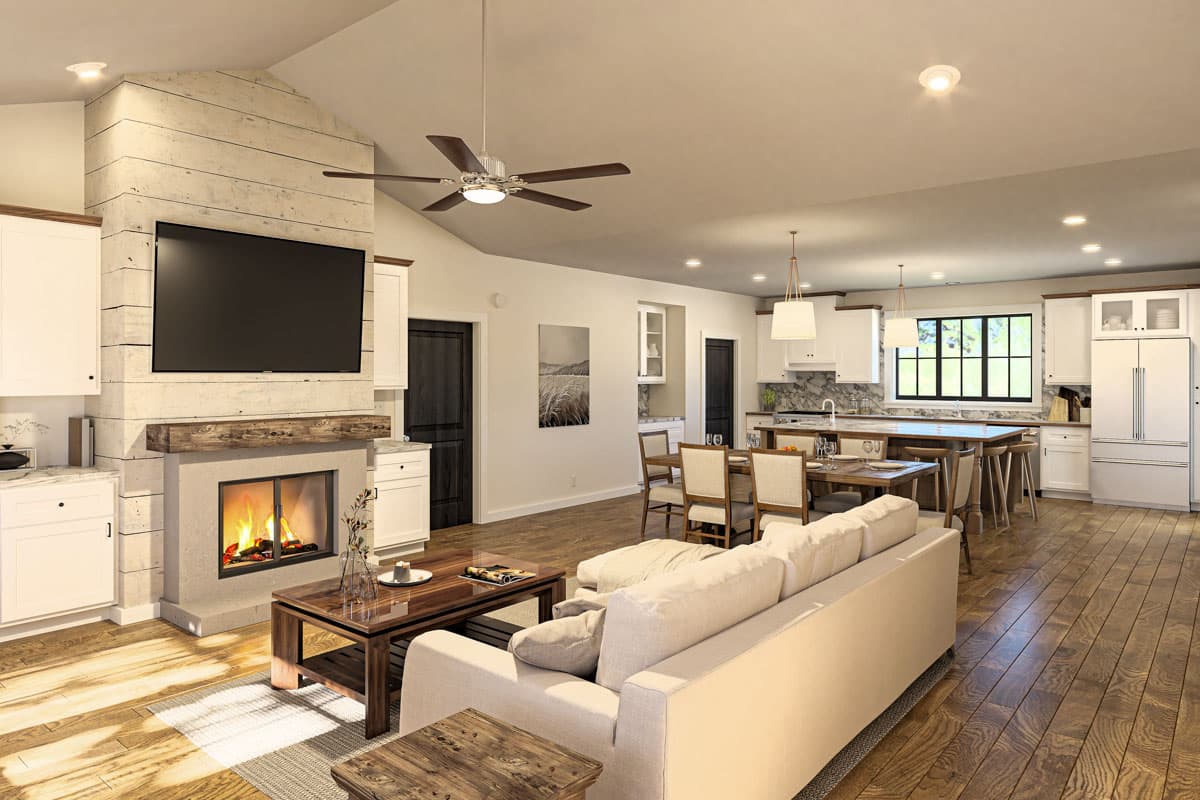 Open concept living area with fireplace, vaulted ceiling, dining area, and kitchen with island and large window.