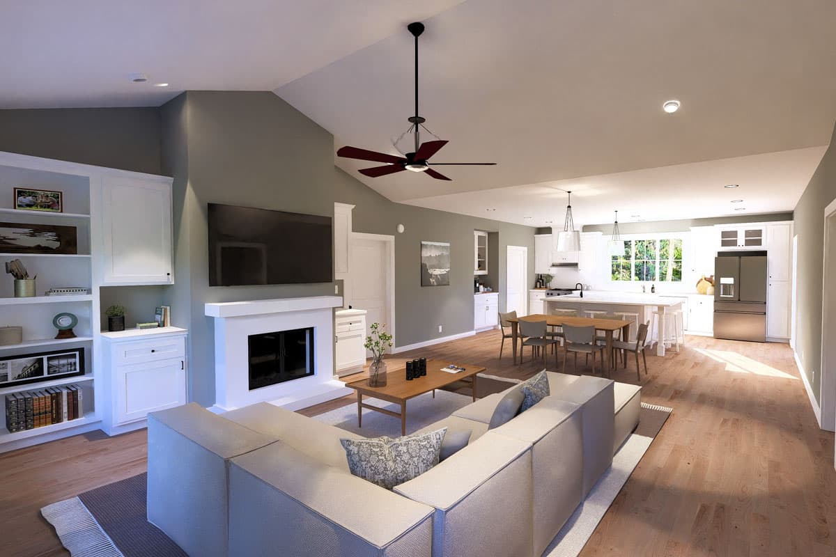 Open concept living area with vaulted ceiling, fireplace, built-in shelving, kitchen island, and dining area.