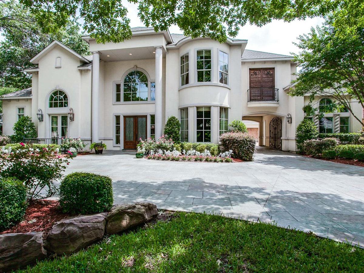 House plan exterior: Two-story stucco home with arched windows, double front doors, columns, and covered entryway.