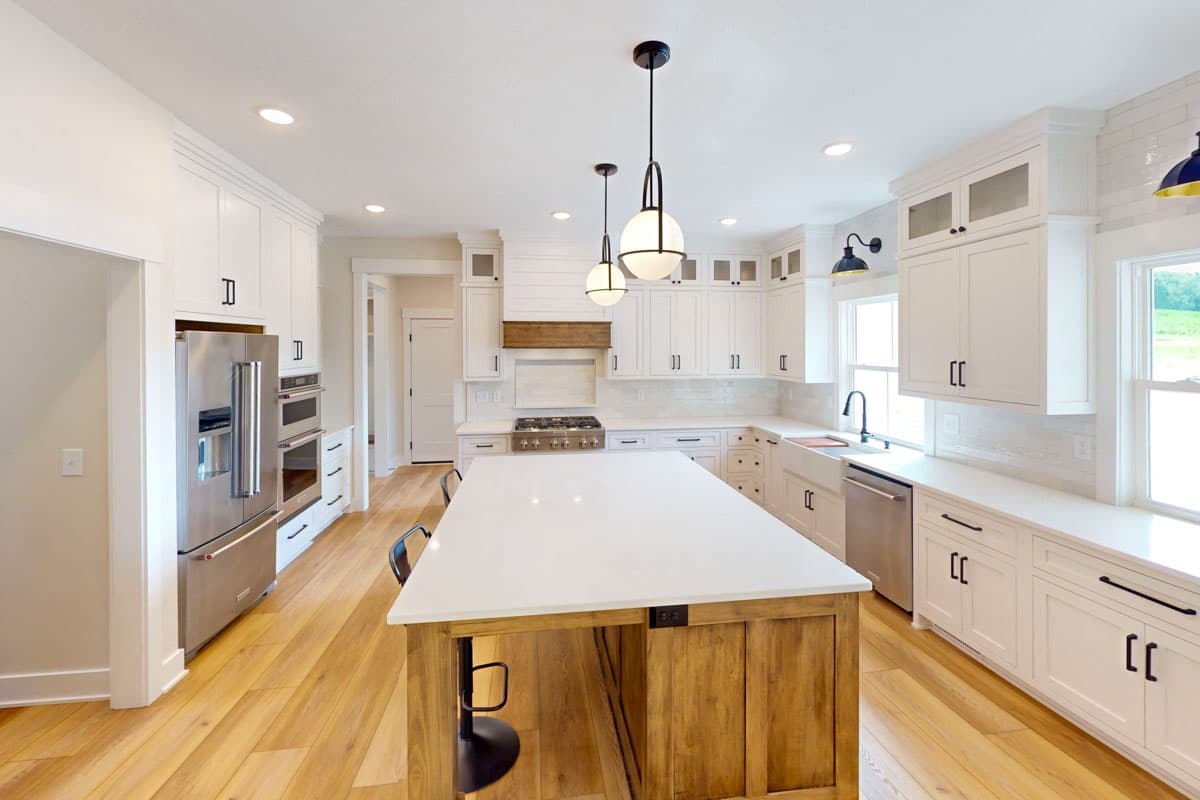 Modern kitchen with white shaker cabinets, a large island with wood base, stainless steel appliances, and hardwood floors.