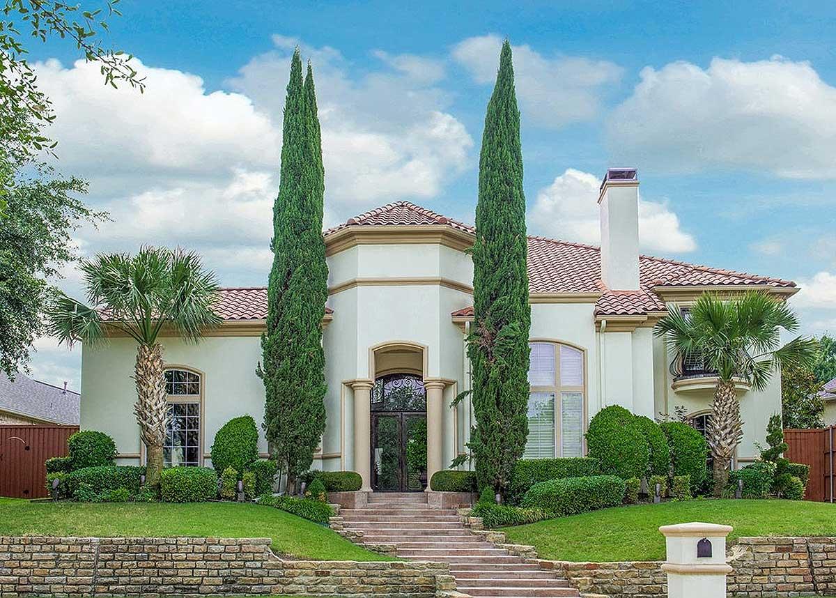 House plan exterior: two-story Mediterranean-style residence with arched entryway, double doors, tile roof, and prominent chimney.