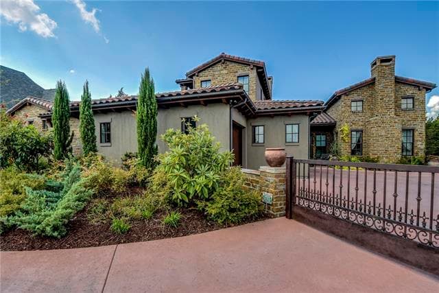 House plan exterior: Tuscan style, multi-story residence with stone accents, arched doorways, and a tiled roof.