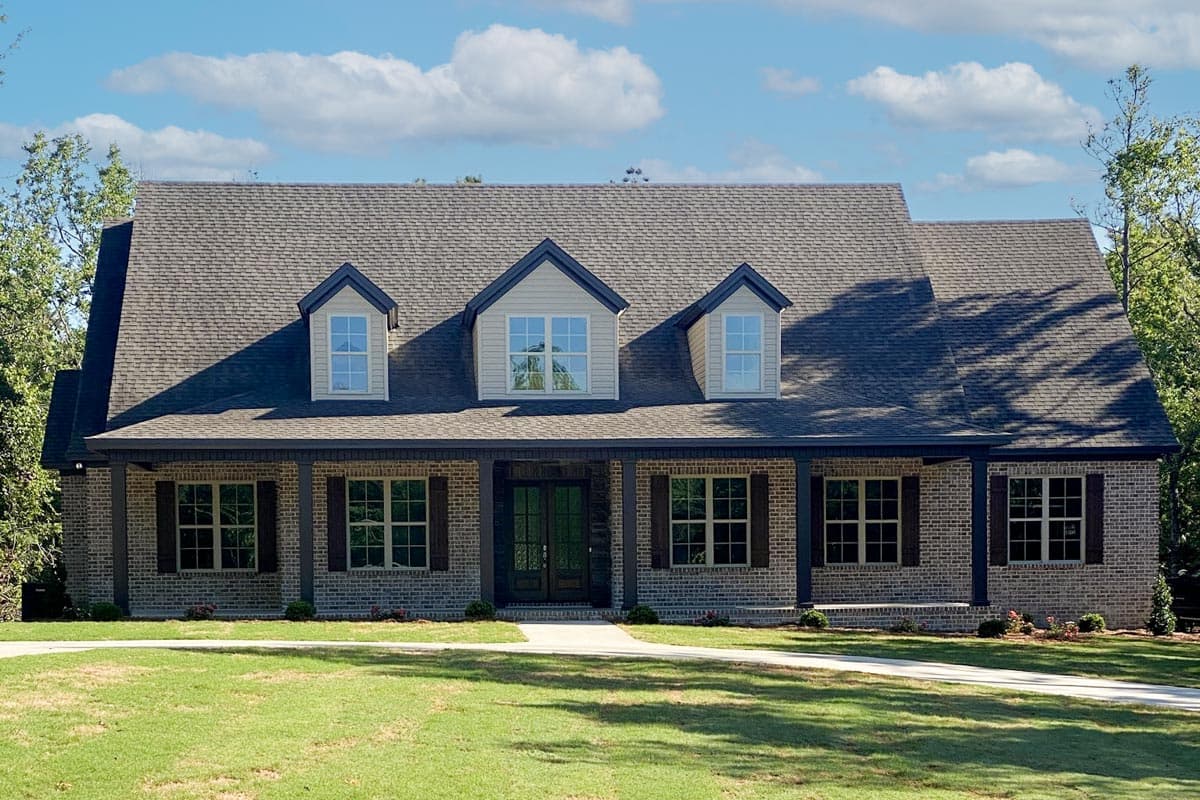 House plan exterior: Traditional two-story brick home with full-width covered porch, gables, and dormer windows.