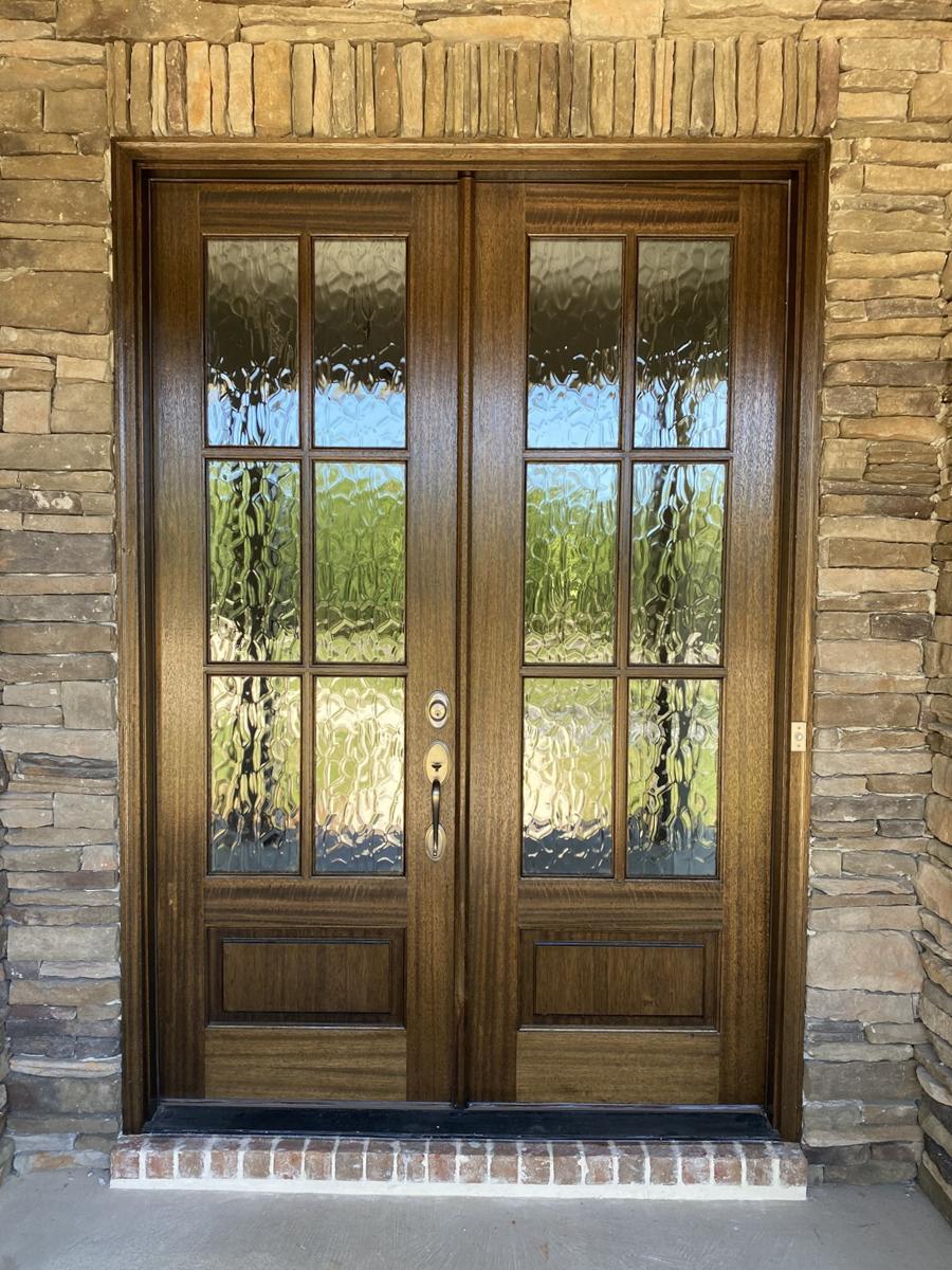 Double wooden doors with glass panels, framed by stacked stone and brick details.
