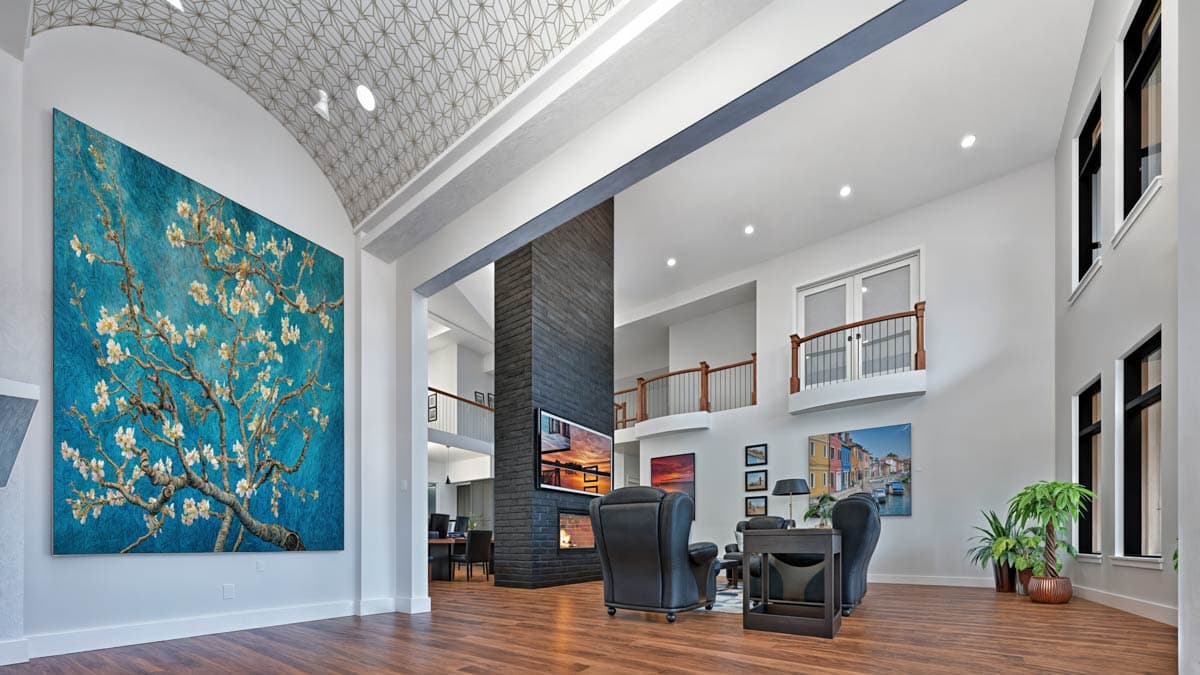 Interior rendering: Open living space with a large fireplace, high ceilings, a second-floor balcony, and a prominent art installation.