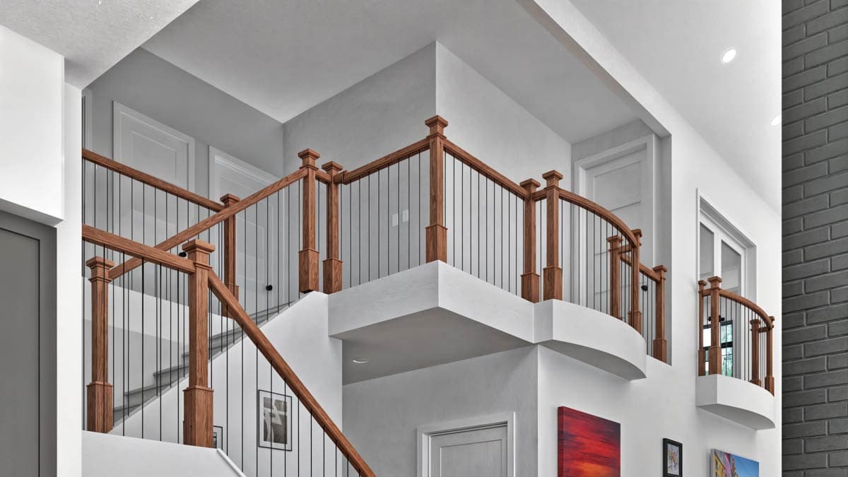 Interior view of a two-story foyer with a staircase featuring wood railings, metal balusters, and curved balconies.