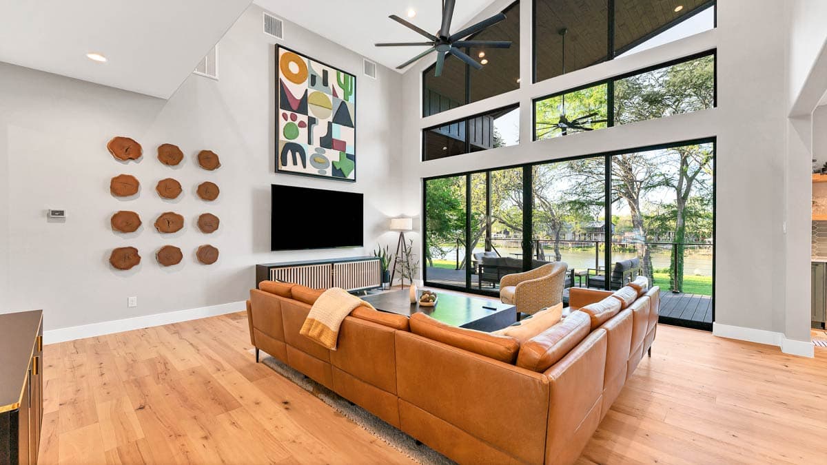 Great room with vaulted ceiling, large windows overlooking water, and sectional sofa.