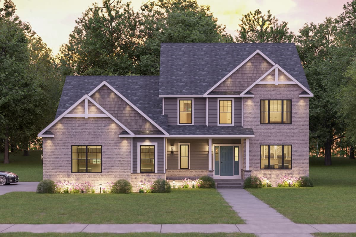 A two-story house with a combination of brick and siding. Landscaping includes bushes and flowers.