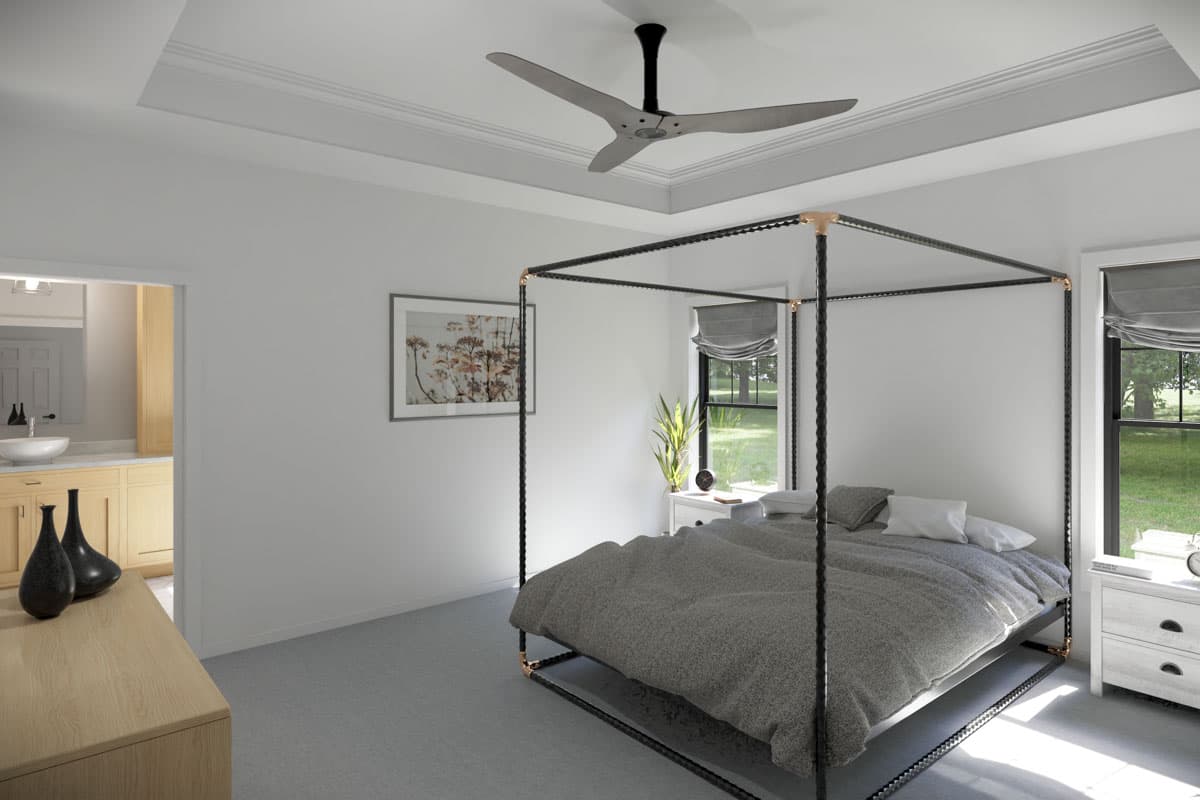 A master bedroom with a canopy bed, artwork, and a view of the outdoors from the window.
