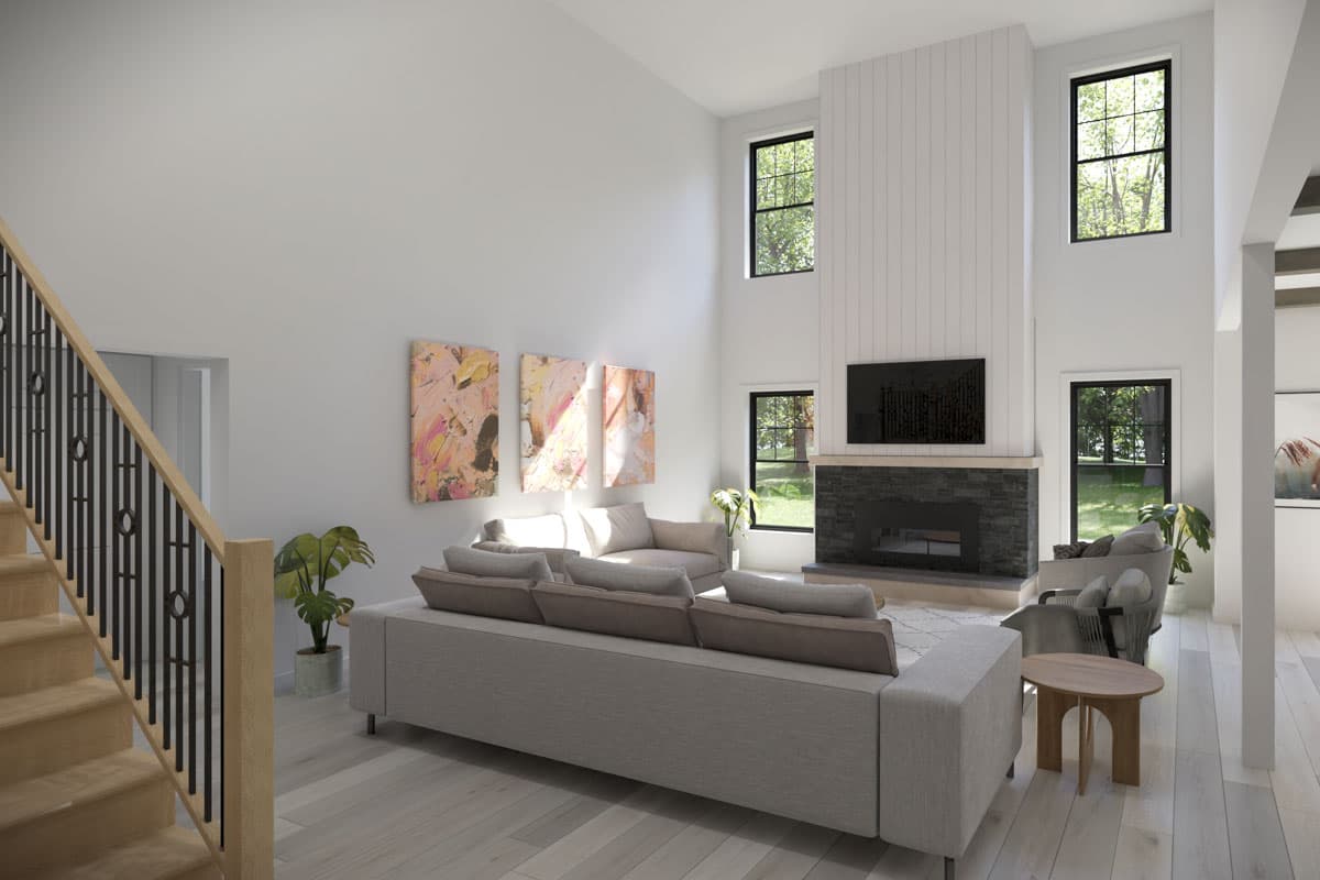 Spacious traditional home interior with a fireplace, abstract art, sofa, and a staircase leading up.