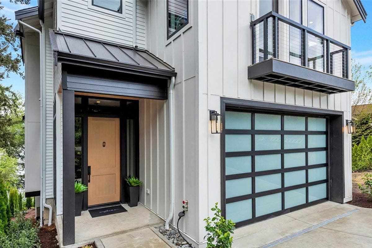Modern house exterior with a covered entry, wood door, frosted glass garage door, and a cantilevered balcony.