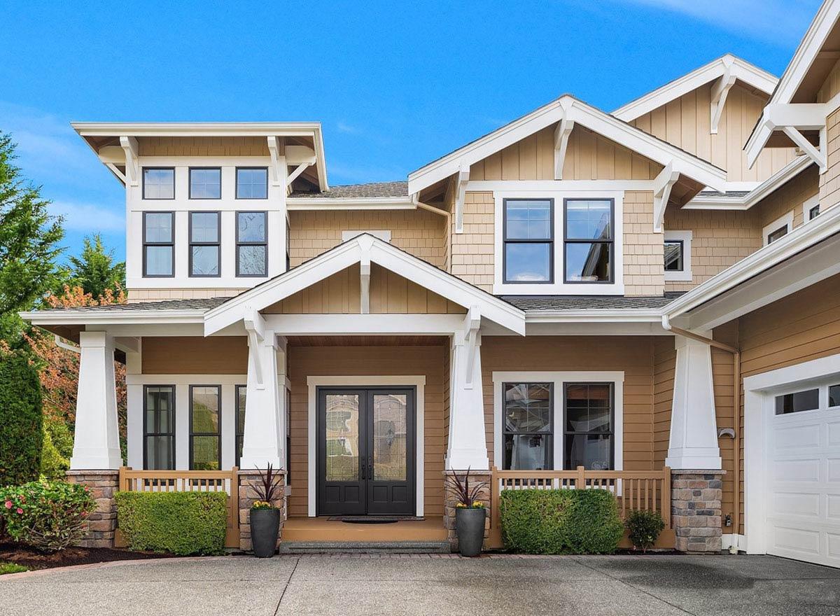 House plan exterior: Craftsman style, two stories, prominent gables, covered porch with columns, and multiple window groups.