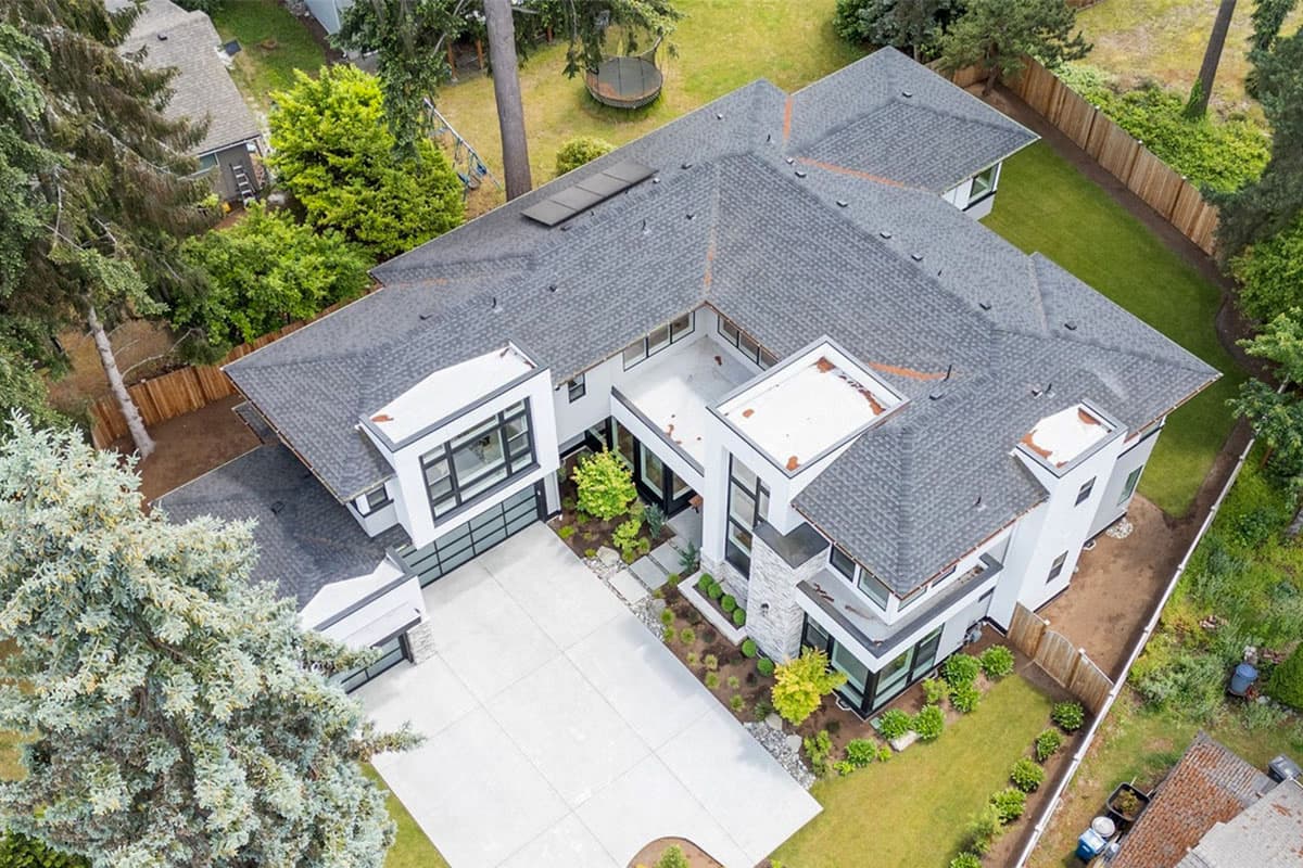 Modern house plan exterior with multiple gables, flat roof sections, large windows, and an attached garage.
